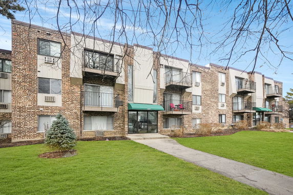 Front view of a multi-story brick apartment building with balconies.
