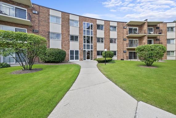 Front view of a three-story apartment building with balconies and a central entrance.
