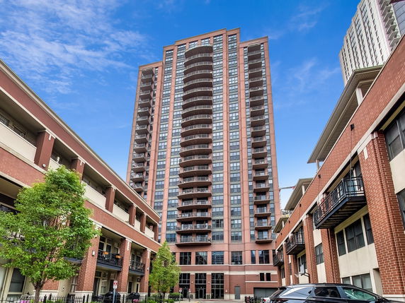 Front view of a tall residential building with multiple balconies and a brick facade.