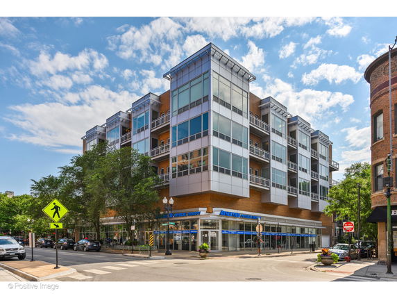 Front view of a modern multi-story building with large windows and balconies.