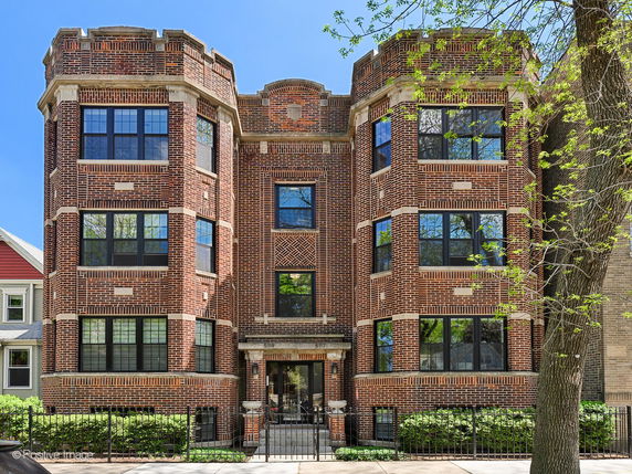 Front view of a multi-story brick building with large windows.