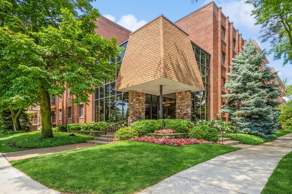Front view of a brick building with large windows and a unique triangular canopy entrance.