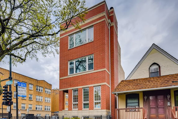 Front view of a red brick residential building with large windows.