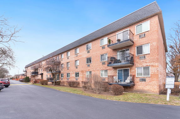 Front view of a multi-story brick apartment building with balconies.