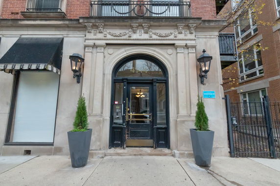 Front view of a building entrance with an ornate arch and decorative facade.
