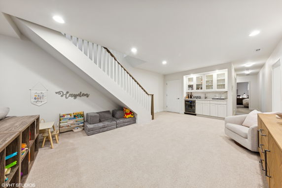 Room with children's play area under stairs, small sofas, and a bar counter.