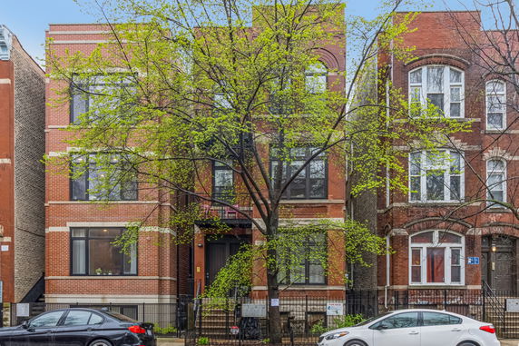 Front view of a multi-story brick building with large windows.