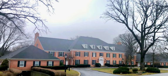 Front view of a large two-story brick building with multiple dormer windows.