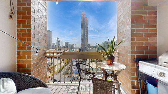 Balcony view showing cityscape with tall buildings and roads.