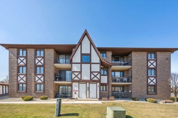 Front view of a multi-story apartment building with brick and Tudor-style design.
