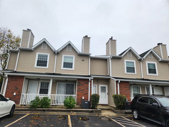 Front view of a townhouse with two levels, featuring gabled roofs and chimneys.