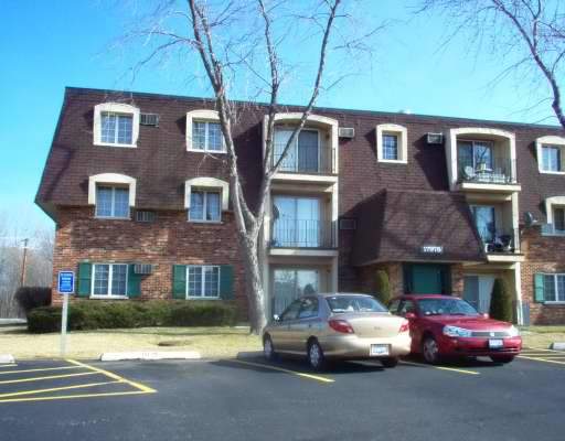 Front view of a three-story apartment building with cars parked in front.