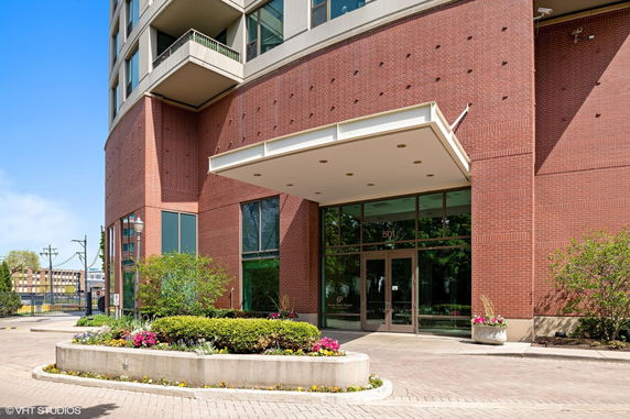Front view of a brick building entrance with large glass doors and a covered entryway.
