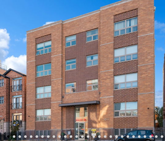 Front view of a multi-story brick building with large windows.