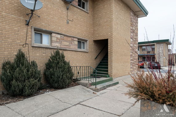 Exterior view of a two-story brick building with satellite dishes and a staircase.