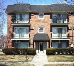 Front view of a three-story brick apartment building with balconies.