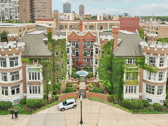 Front view of a multi-story brick building with turrets and ivy-covered walls.
