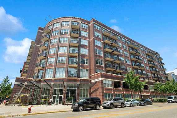 Front view of a multi-story brick apartment building with balconies.