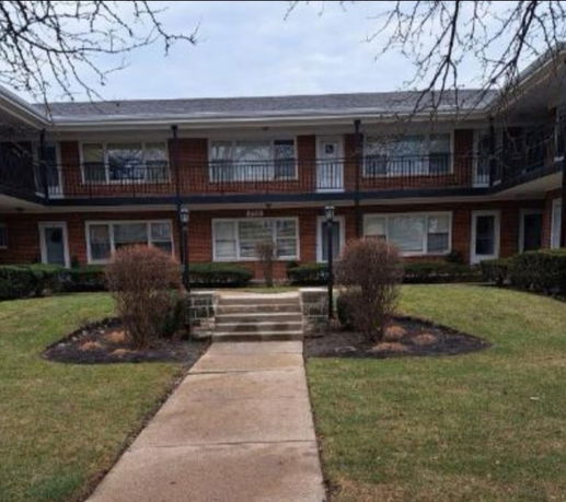Front view of a two-story apartment building with an exterior staircase.