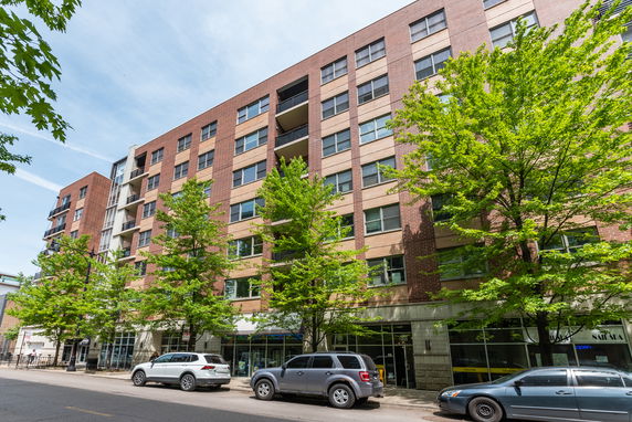 Front view of a multi-story apartment building with brick facade and large windows.