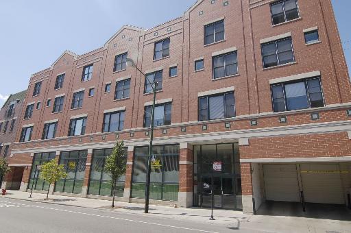 Front view of a multi-story brick building with large windows and a garage entrance.