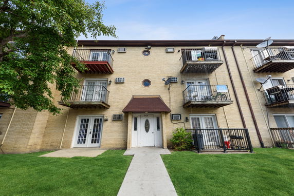 Front view of a multi-story apartment building with balconies.