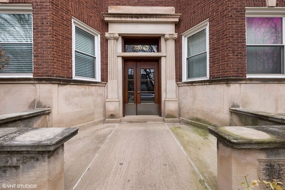 Front view of a brick building entrance with symmetrical windows and classic stone accents.
