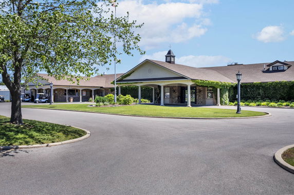 Front view of a single-story building with a covered entrance and ivy-covered walls.