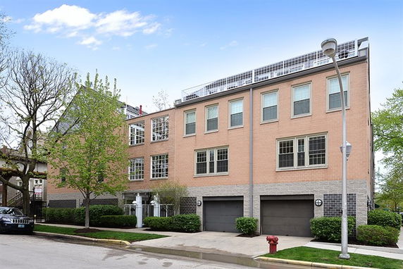 Front view of a multi-story residential building with garages on the ground floor.