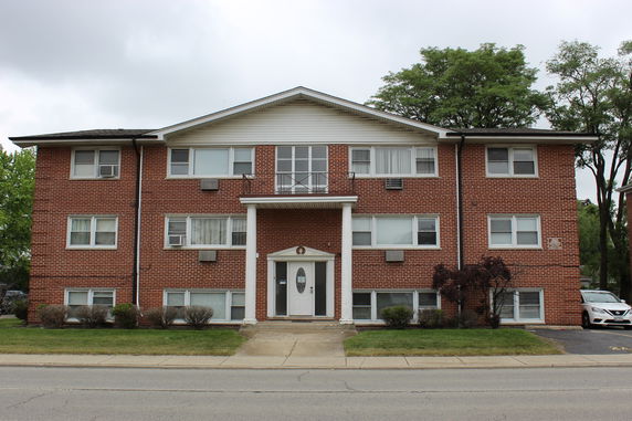Front view of a three-story brick apartment building with a central entrance and symmetrical windows.
