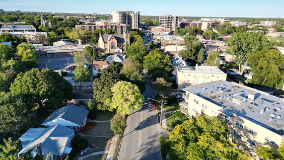 Panoramic view of a suburban area with houses, trees, and buildings under a clear sky.