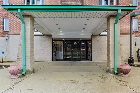 Front view of a building entrance with a green canopy and brick exterior.