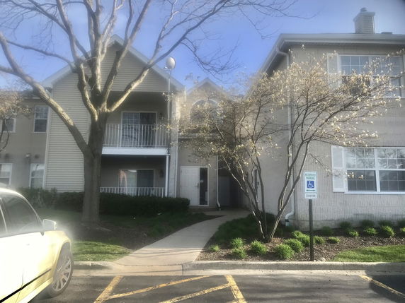 Front view of a residential building with balconies and a reserved parking sign.