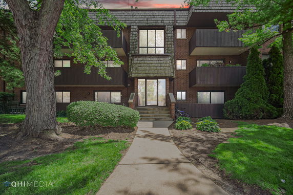 Front view of a multi-story residential building with balconies and a central entrance.
