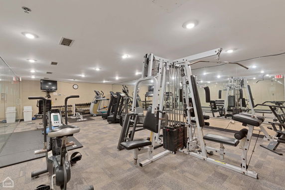 Indoor gym area with various exercise equipment and a mirrored wall.