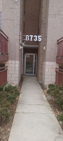 Entrance view of a brick apartment building with a narrow walkway.