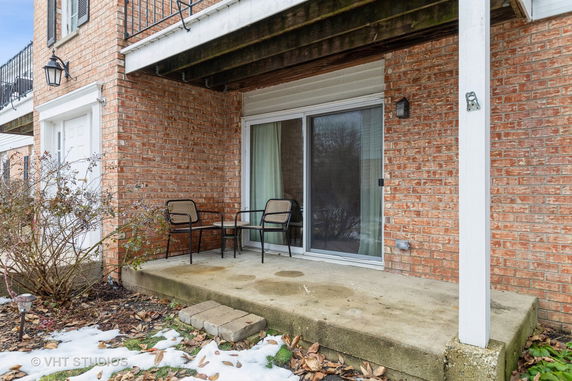 Front view of a brick building with a small patio and sliding glass door.