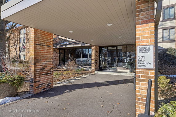 Front view of a building entrance with brick pillars and glass doors.
