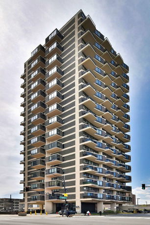 Front view of a modern multi-story apartment building with balconies.