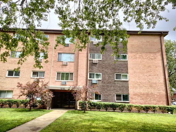 Front view of a multi-story apartment building with brick facade.