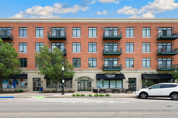 Front view of a multi-story brick building with balconies and large windows.
