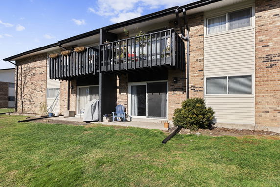 Front view of a two-story apartment building with balconies and sliding glass doors.
