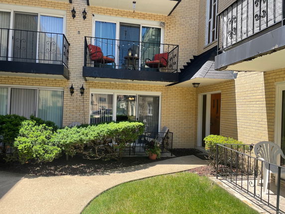 Front view of a multi-story residential building with balconies and a landscaped entrance.