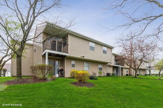 Front view of a two-story residential building with a small balcony and siding exterior.