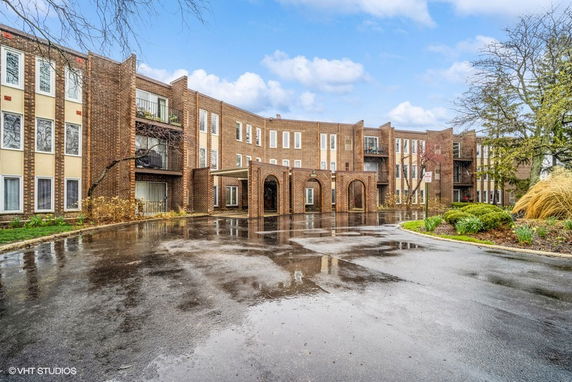 Front view of a multi-story brick building with an arched entrance.