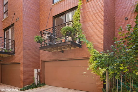 Front view of a brick building with metal balconies and a double garage.