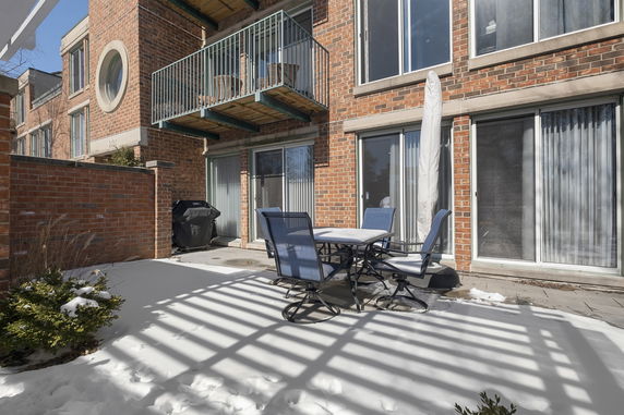 Brick residential building with balconies and patio furniture in a snowy outdoor setting.