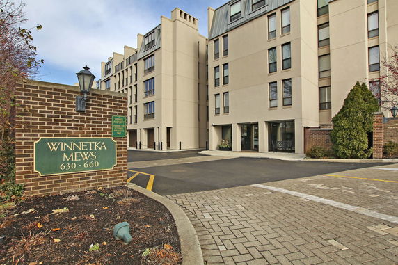 Front view of a multi-story building with a brick sign labeled 'Winnetka Mews 630-660.'