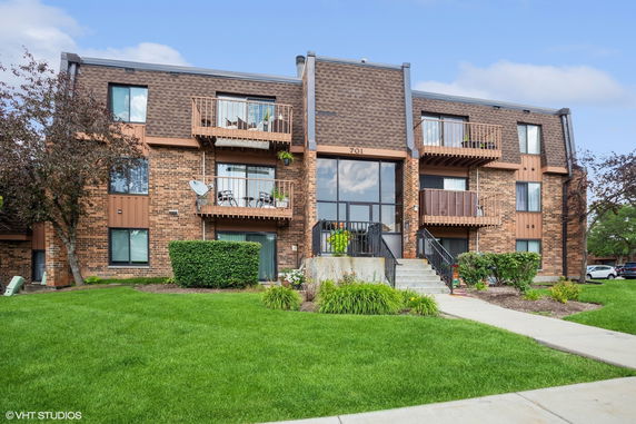 Front view of a three-story brick apartment building with balconies.