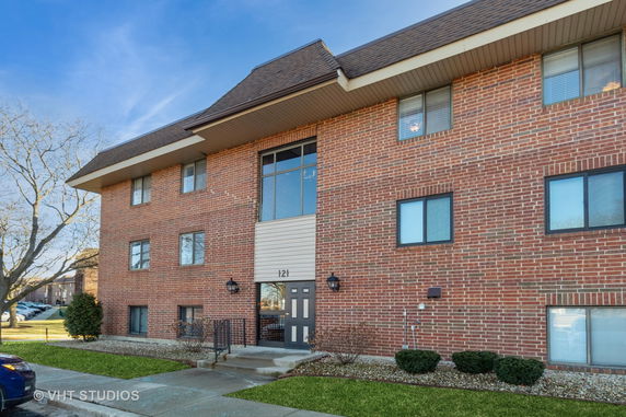 Front view of a brick multi-story building with a central entrance and multiple windows.